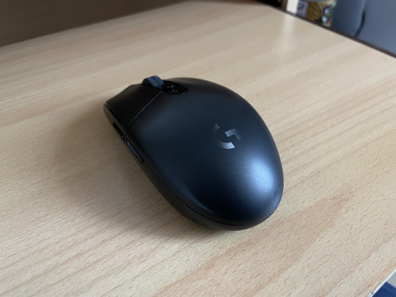 Black Logitech G305 wireless gaming mouse on a wooden desk